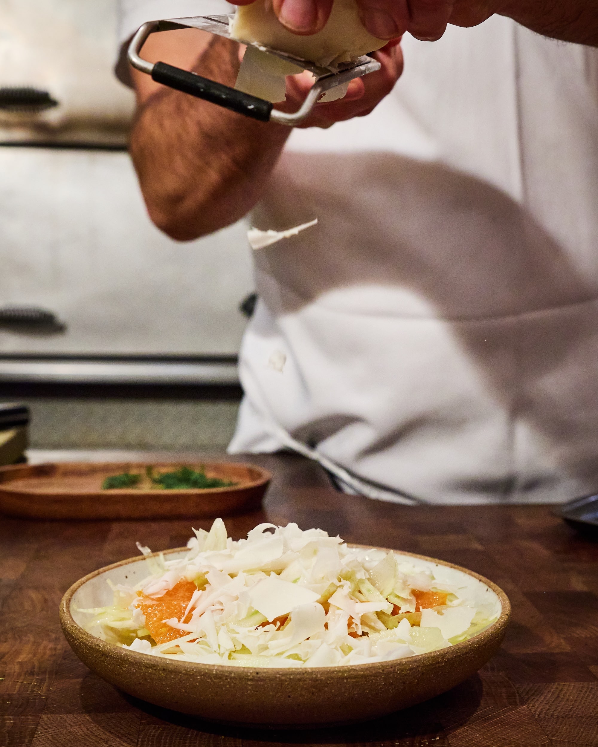 Chef shaving Manchego onto a dish