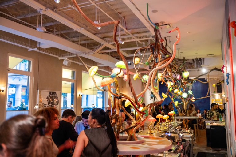 Restaurant interior with twisting pieces of wood and mushroom light fixtures spiraling down from the ceiling. People are sitting and enjoying themselves.