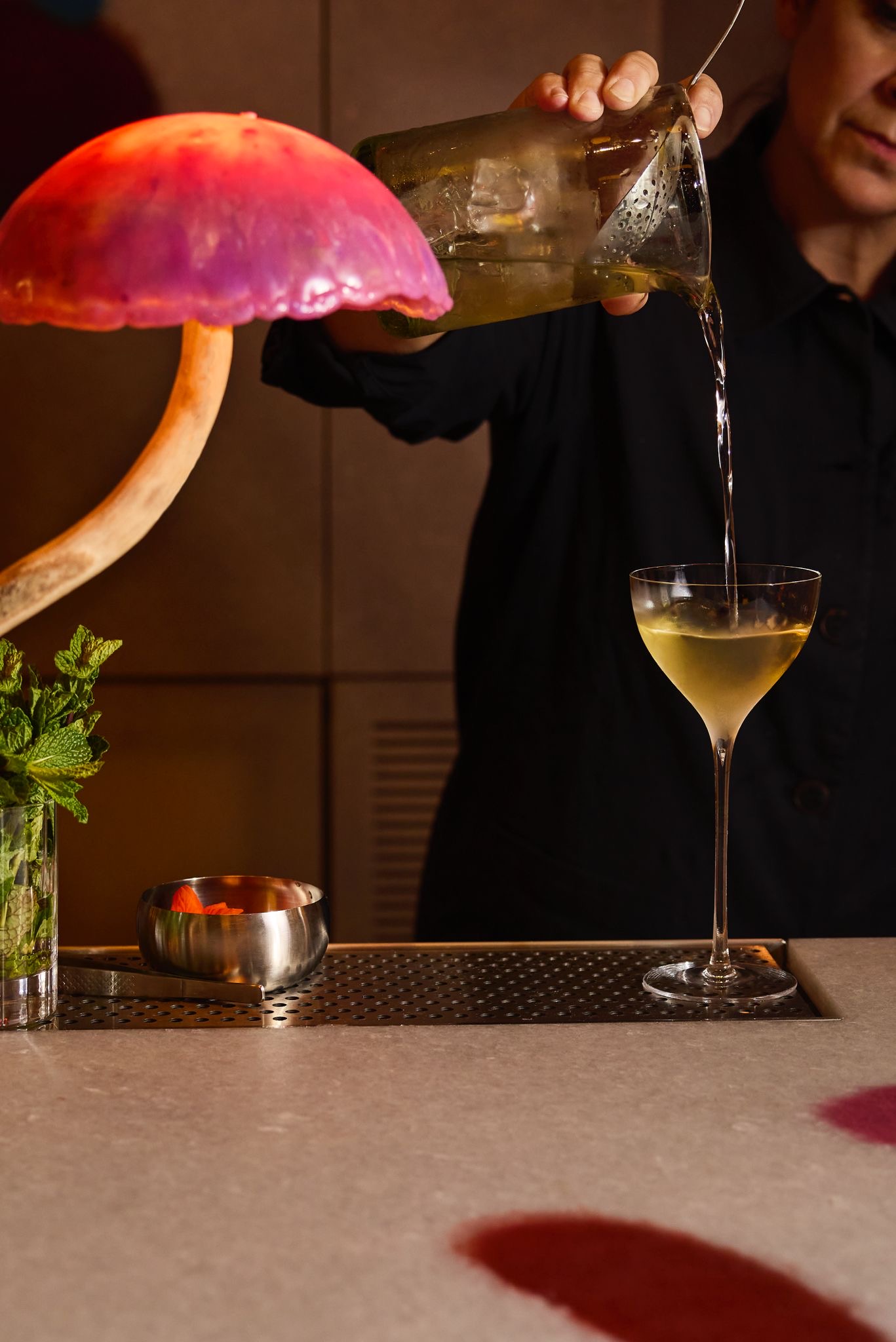 Stirred cocktail being poured into a stemmed cocktail glass