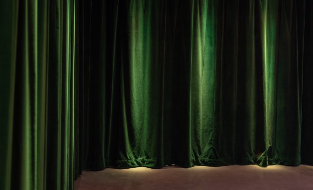 Green curtains in the Black Box Theatre beneath Manuela