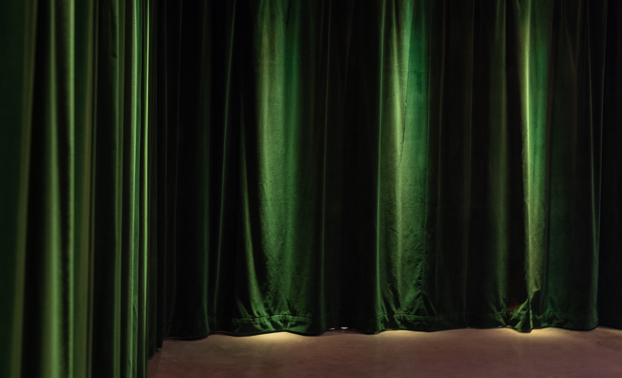 Green curtains in the Black Box Theatre beneath Manuela